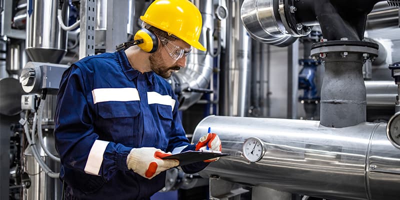A worker in PPE inspecting machinery